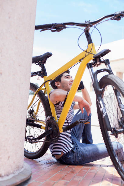 istock Young man using his cell phone while resting riding a bicycle in the street 1193434344