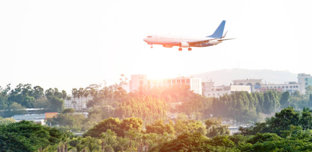 istock Airplane flying over trees and buildings 1193442712