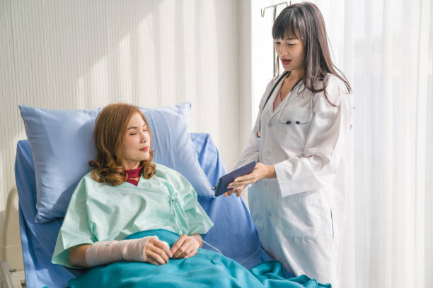 istock Senior patient female folding broken arm with bandaging the hand using digital tablet and credit card making online payment while  sitting on wheelchair  at the hospital 1193449185