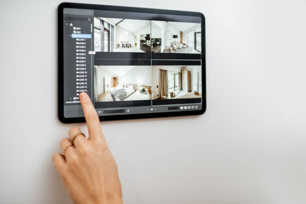 Controlling home with video cameras and digital tablet Controlling home with video cameras and digital tablet. Concept of remote video surveillance over the internet with smart touch screen devices indoor security camera stock pictures, royalty-free photos & images