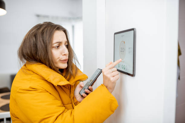 istock Cold woman controlling heating with a smart devices 1193452880