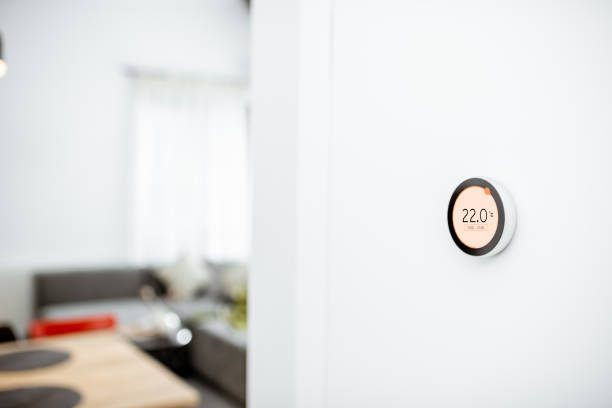 Smart home heating system Round smart thermostat with touch screen installed on the wall indoors. Smart home heating regulation concept. View with copy space smart thermostat photos stock pictures, royalty-free photos & images