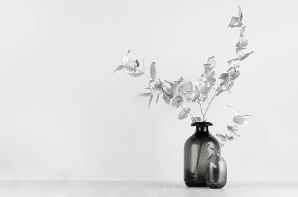 istock Elegant black glass bottles as home decor on soft light white wood table with silver decorative leaves, copy space. 1193454729