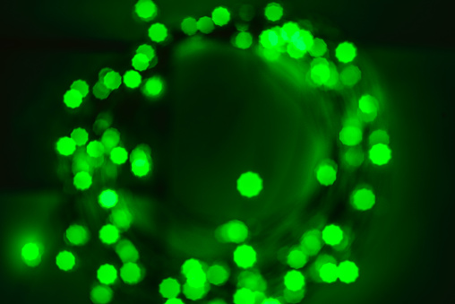 Shiny golden green bokeh in circle on black background. Festive background concept. Christmas, New Year, party.