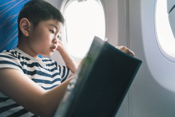 istock Young boy reading book in airplane 1193456135