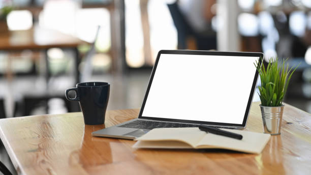 istock Laptop computer, coffee, notebook and pen on wooden table on co working background. 1193457420