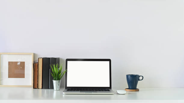 istock Workspace laptop computer, book, photo frame and coffee mug with plant pot on copy space white table. 1193457742