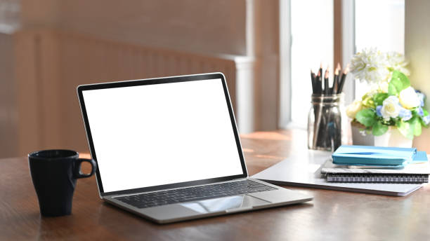 istock Empty screen laptop computer, notebook, pencil holder with flower and coffee cup on wood table. 1193457790