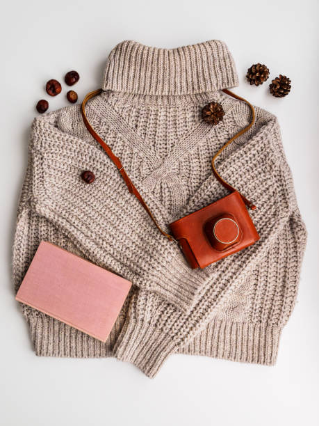 istock A warm wool sweater and an old camera in a brown case. Book, cones and chestnuts 1193459150