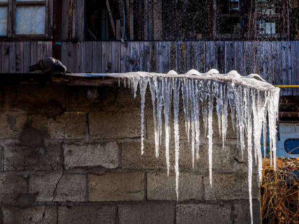 сосульки на крыше дома от утечки воды из лопнухаем трубы - melting ice icicle leaking стоковые фото и изображения
