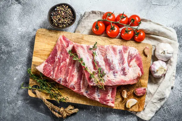 Photo of Fresh raw pork ribs with rosemary, pepper and garlic. Farm organic meat. Gray background. Top view