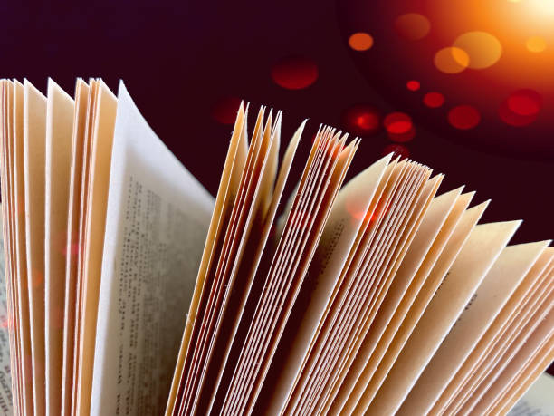 istock Ajar pages in the book. Old hardback textbook, on black background. Concept: education, training, love of knowledge. 1193462783