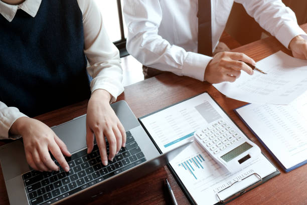 istock Businessman analyzing investment charts and pressing calculator buttons over documents. Accounting Concept. 1193464708