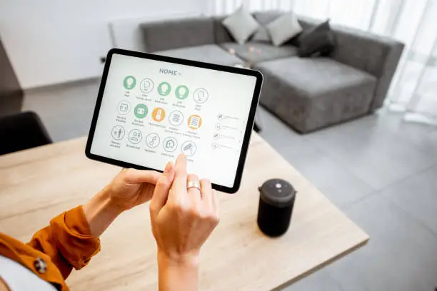 Photo of Woman controlling smart devices with a digital tablet at home