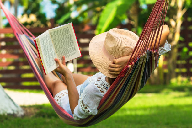 Woman reading book in hammock Woman reading book in hammock in tropical garden leisure activity stock pictures, royalty-free photos & images