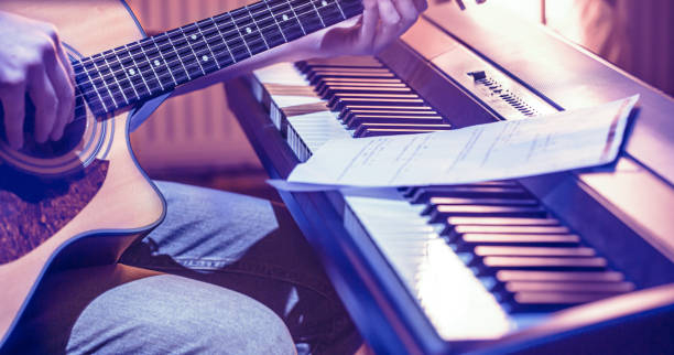 istock man playing acoustic guitar and piano close-up, recording notes 1193474496