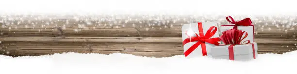 Wide horizontal composition of red ribbon gifts group on wooden background with snowfall. Blank white space for text.