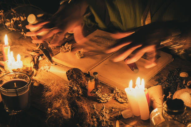 manos adivino sobre una mesa antigua con hierbas y libros. manifestación del ocultismo en forma de adivinación - bruja fotografías e imágenes de stock