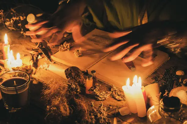 Hands fortune teller over an ancient table with herbs and books. Manifestation of occultism in the form of divination.