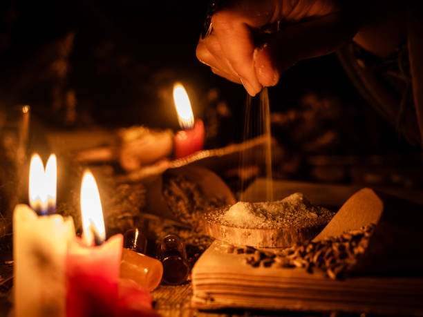 istock A witch sprinkles salt for a magical ritual. Candles are burning on the old table. Attributes of occultism and magic 1193478041