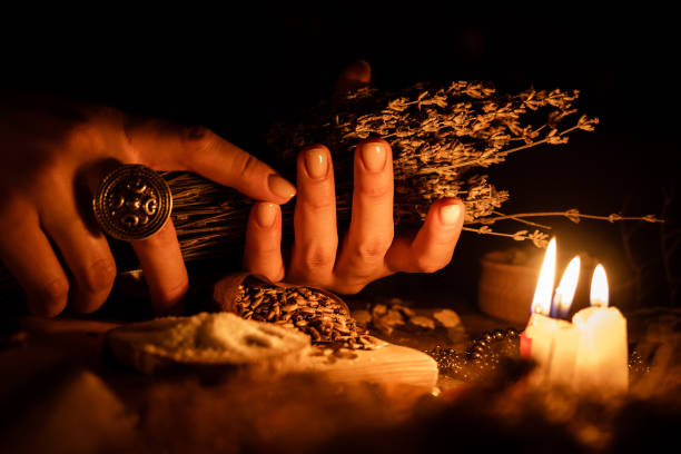 в руках ведьм куча сухих трав для гадания. свет от свечей на старом волшебном столе. атрибуты оккультизма и магии - occultism стоковые фото и изображения