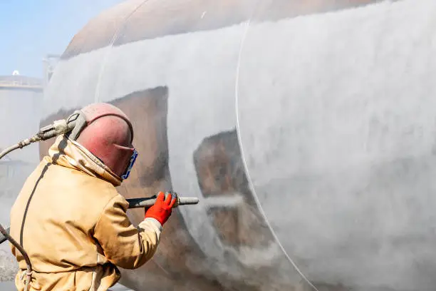 Photo of Close up view of sandblasting before coating. Abrasive blasting, more commonly known as sandblasting, is the operation of forcibly propelling a stream of abrasive material against a surface.
