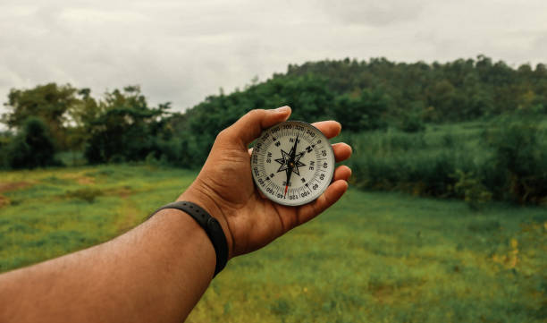 HOLDING COMPASS IN HAND FOR FINDING DIRECTION stock photo