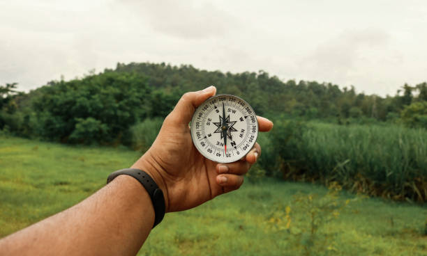 HOLDING COMPASS IN HAND FOR FINDING DIRECTION stock photo