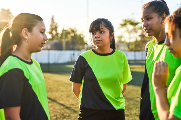 Female captain discussing with soccer team Soccer girl discussing game plan with team. Females are listening to captain. They are in sportswear. soccer team captain stock pictures, royalty-free photos & images