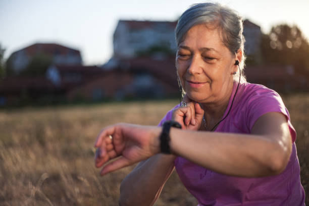 mujer senior revisando su pulso después del ejercicio - human artery audio fotografías e imágenes de stock