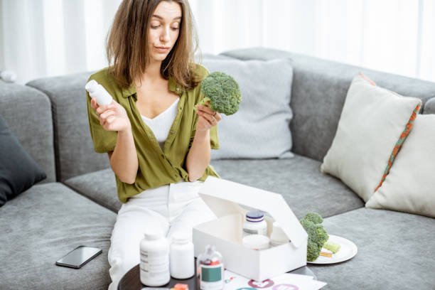 istock Thoughtful woman with nutritional supplements and broccoli at home 1193488921