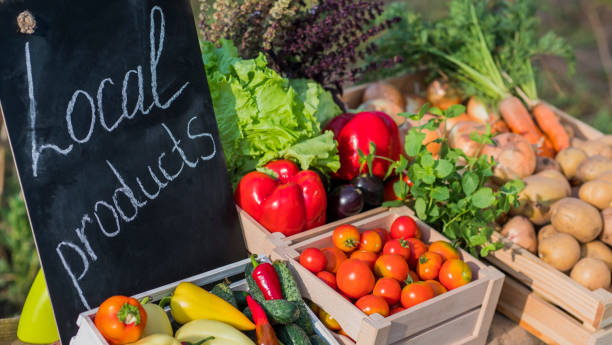 contador con verduras frescas y un signo de productos locales - mercado fotografías e imágenes de stock