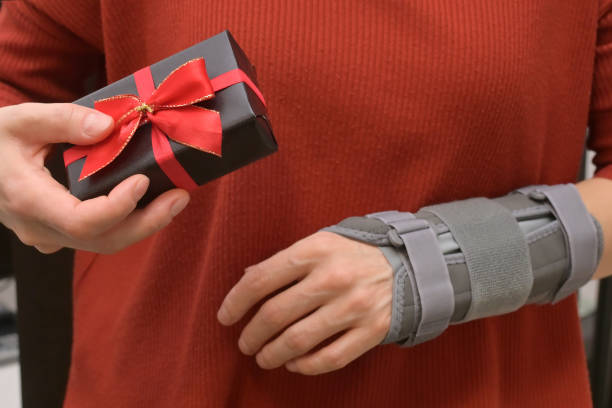 Woman With Gift box and Contused Hand In Stabilizer stock photo