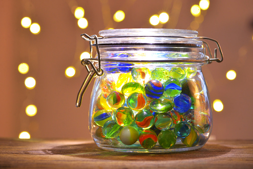 close up photo of glass jar filled with jelly beans, glass jar lid, and free jelly beans outside of jar on white background