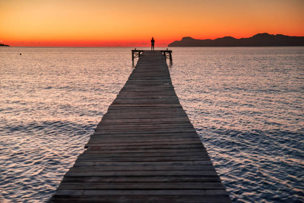 istock silhouette a woman on pier at coast. 1193493079