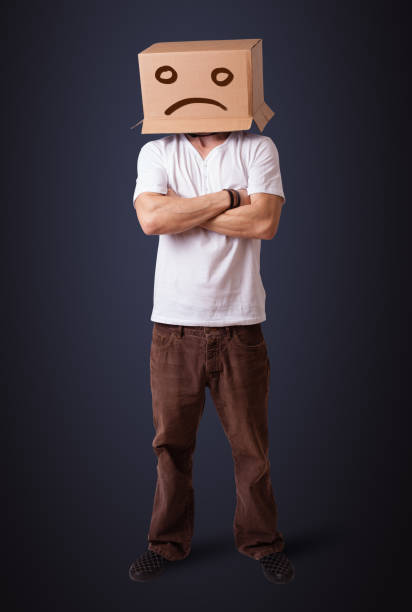 istock Young man with a brown cardboard box on his head with sad face 1193494455