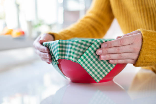 Close Up Of Woman Wrapping Food Bowl In Reusable Environmentally Friendly Beeswax Wrap Close Up Of Woman Wrapping Food Bowl In Reusable Environmentally Friendly Beeswax Wrap plastic free photos stock pictures, royalty-free photos & images