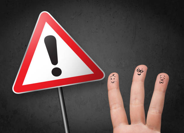 istock Happy smiley fingers looking at triangle warning sign with exclamation mark 1193497323