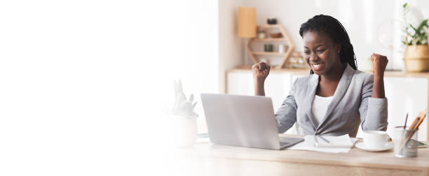 Excited African American Businesswoman Celebrating Success At Workplace Business Success. Excited African Businesswoman Celebrating Success At Workplace, Raising Hands And Looking At Laptop, Panorama With Free Space excitement laptop stock pictures, royalty-free photos & images