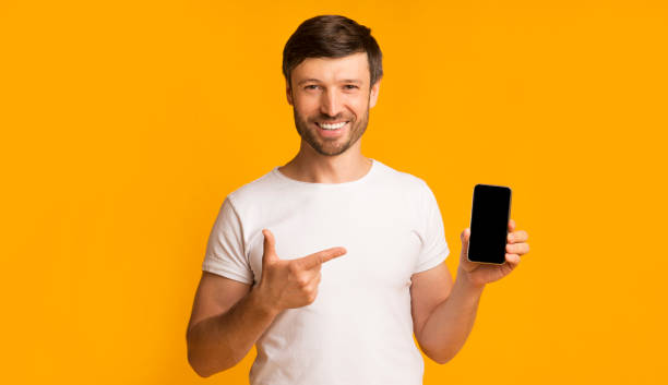 istock Man Showing Smartphone Blank Screen Smiling On Yellow Background, Mockup 1193498057
