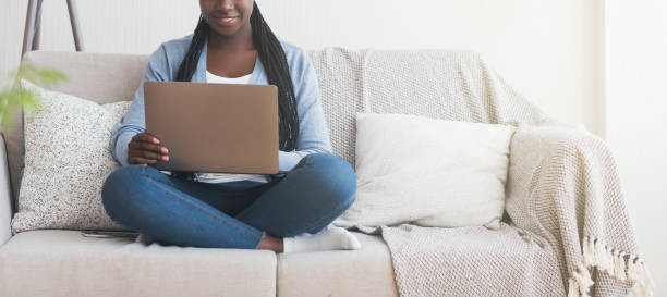 istock Unrecognizable afro girl using laptop while sitting on sofa at home 1193498489