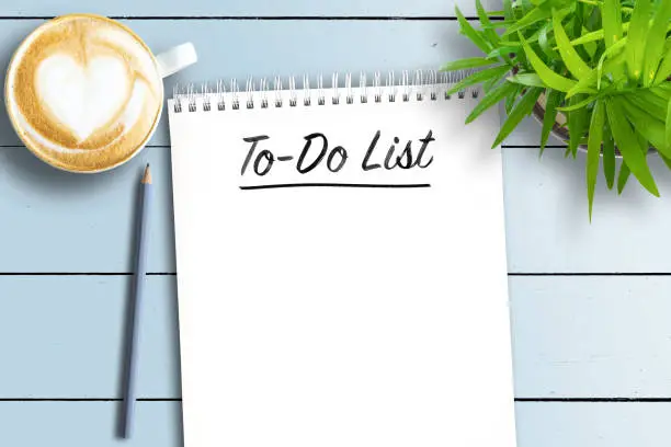 Photo of spiral bound notebook with To-Do List on white wooden table with potted plant and cup of coffee