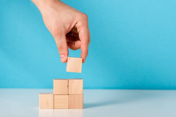 istock cropped view of man putting wooden cube on blue 1193498908