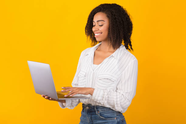 istock Smiling african american girl holding personal computer 1193499789