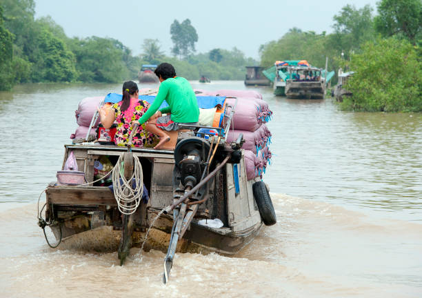 Full house, Mekong River, South Vietnam Houseboat, Mekong River, South Vietnam. Water craft traffic such as barges, houseboats, passenger craft, industrial freighters and small personal boats travel the green rippled waters of the channels and routes of the mighty Mekong River as it flows to the Mekong Delta, South Vietnam small houseboats stock pictures, royalty-free photos & images