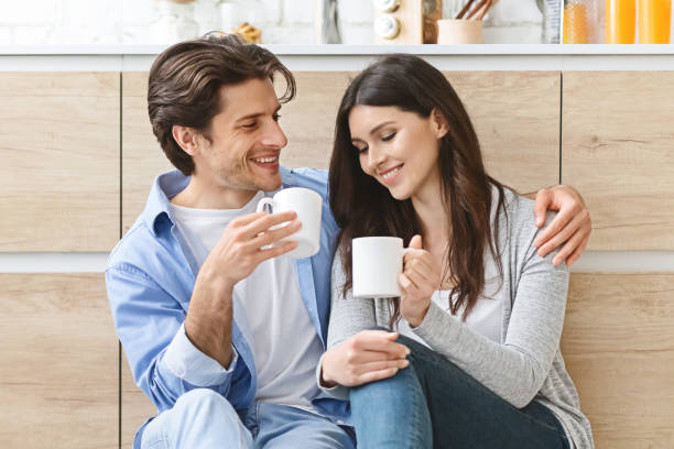 istock Cheerful millennial couple with coffee embracing at kitchen 1193503502