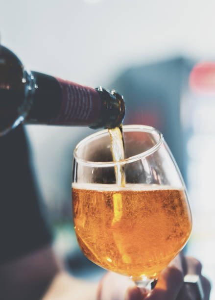 istock pouring beer in glass from bottle on bar or pub 1193503725