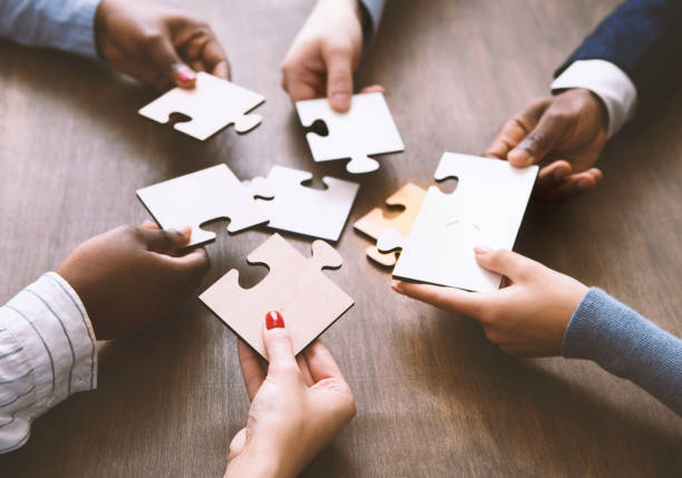 istock Colleagues assembling jigsaw puzzle together at office 1193503760