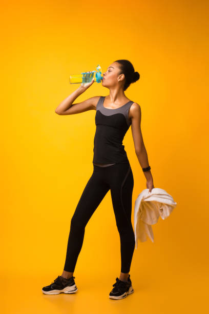 deportiva afroamericana lady agua potable durante el entrenamiento en el estudio - aerobics beautiful bottle body fotografías e imágenes de stock