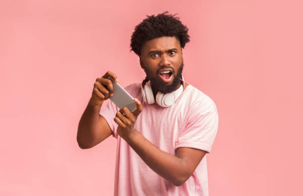 istock Excited black guy holding smartphone and playing mobile games 1193504193